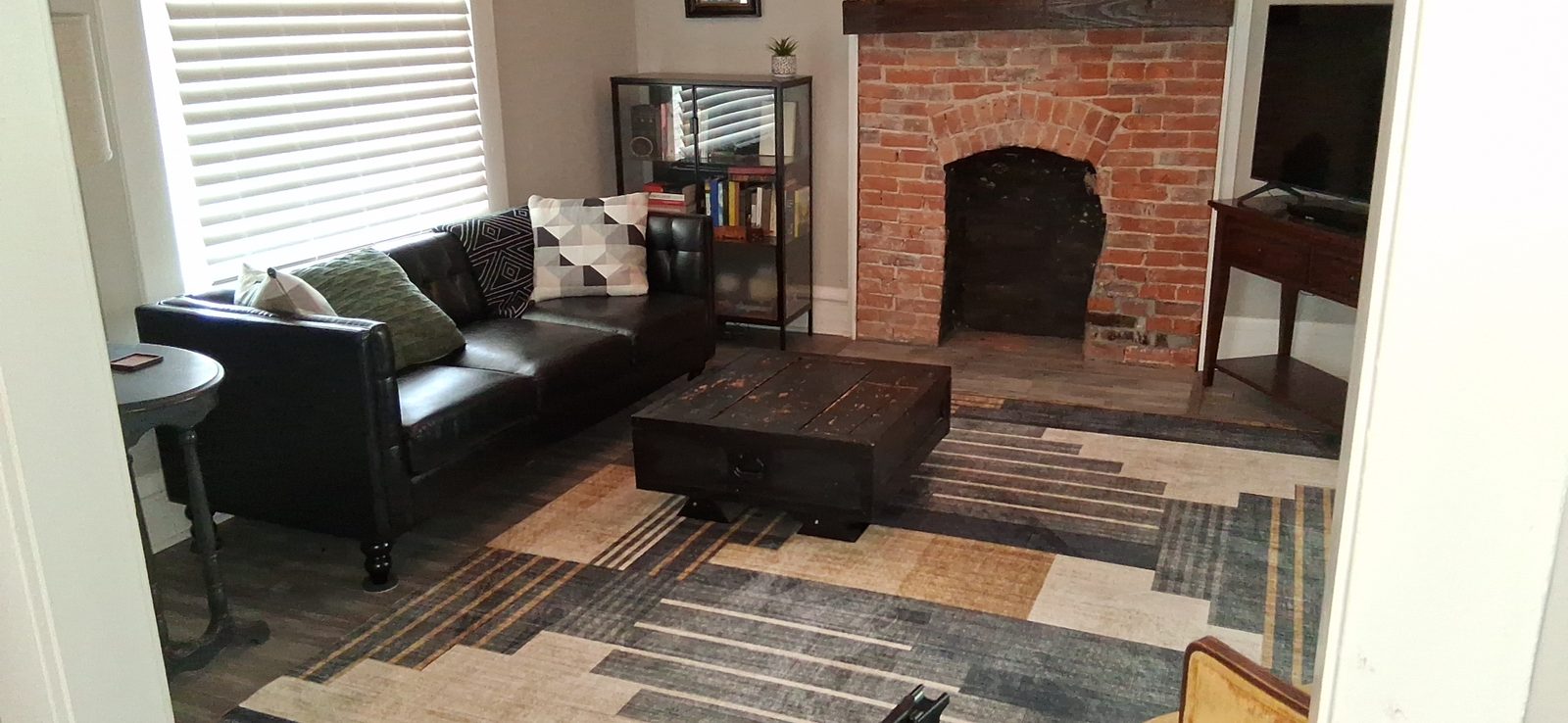 Living room after a turnover clean Short-term rental living room with exposed brick fireplace, leather seating and layered rugs after a turnover