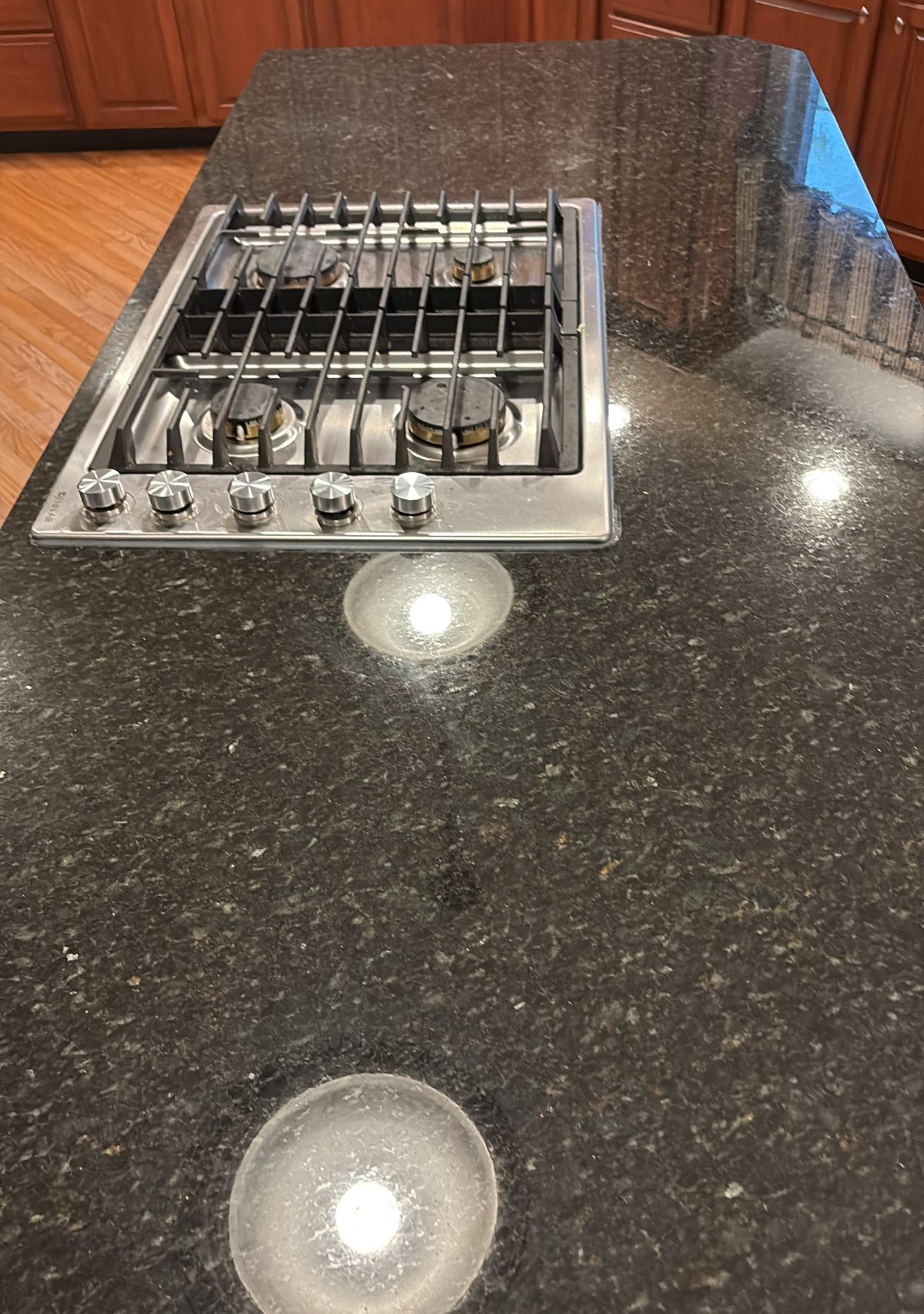Polished granite countertop and gas cooktop after detailed kitchen cleaning