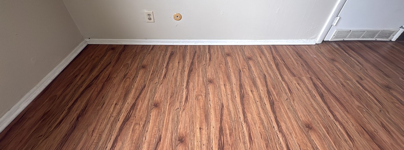 Baseboard and floor-edge detail work Painted baseboard and floor edge along a cleaned wood-look floor